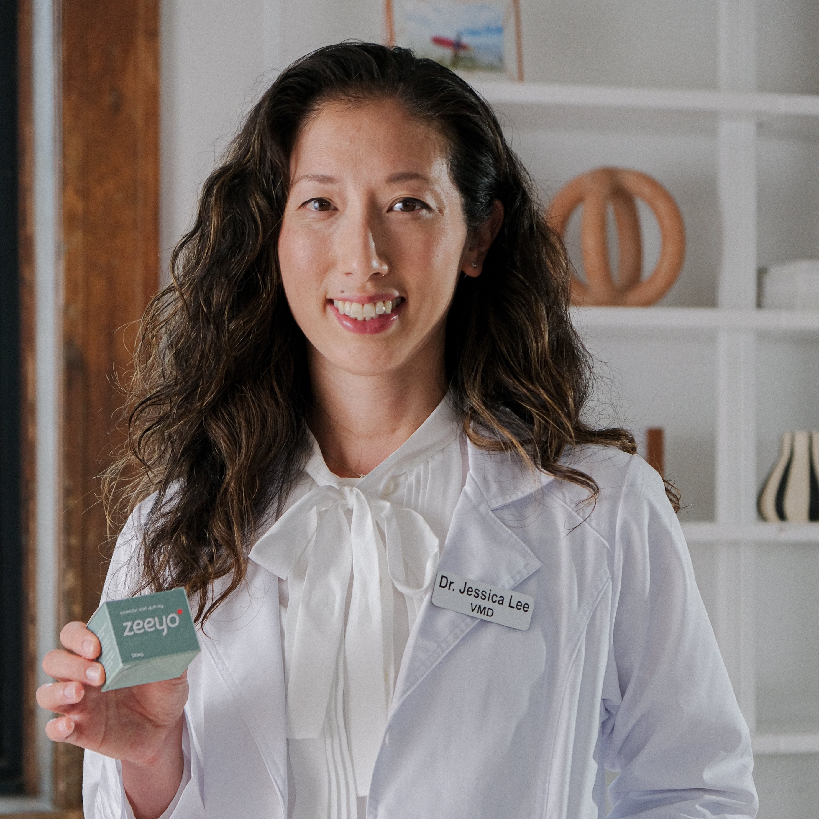 A woman in a white lab coat holding a dog toothpaste